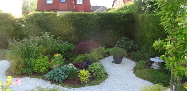 Ein Garten mit einem Kiesweg, umgeben von verschiedenen Pflanzen in der Mitte.